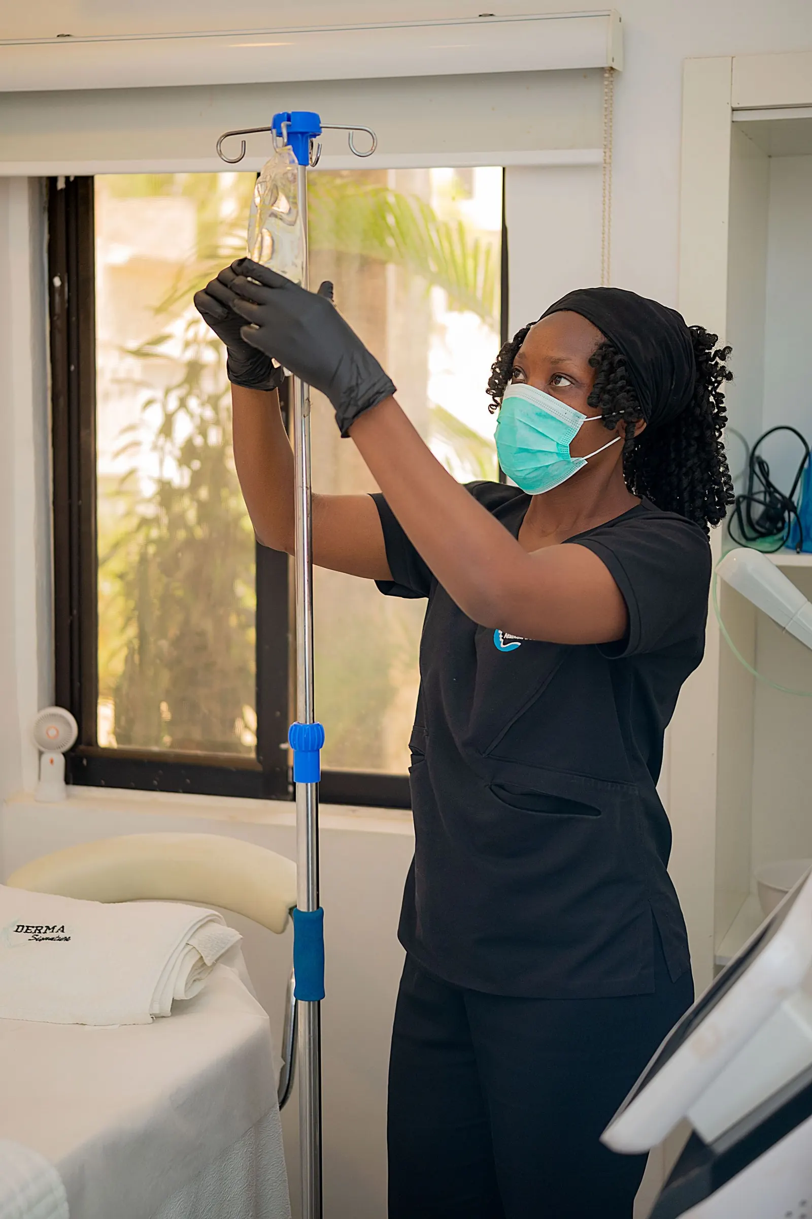 Nurse in dark scrubs adjusting an IV drip beside a treatment bed